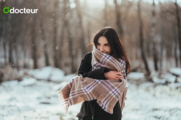 Une écharpe qui entoure le nez et la bouche d'une personne marchant sous un ciel hivernal, protégeant les voies respiratoires du froid et des allergènes qui sont essentiels pour une respiration saine en hiver.
